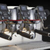 Close-up view of the La Cimbali M200 espresso machine with three brewing heads, digital controls, and ergonomic handles